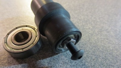 This shows how it fits together. The M4 screw goes through both bearings, then nuts or spacers hold the bearing inner races together. The big bearing is a 608, the one in the roller is a 624.